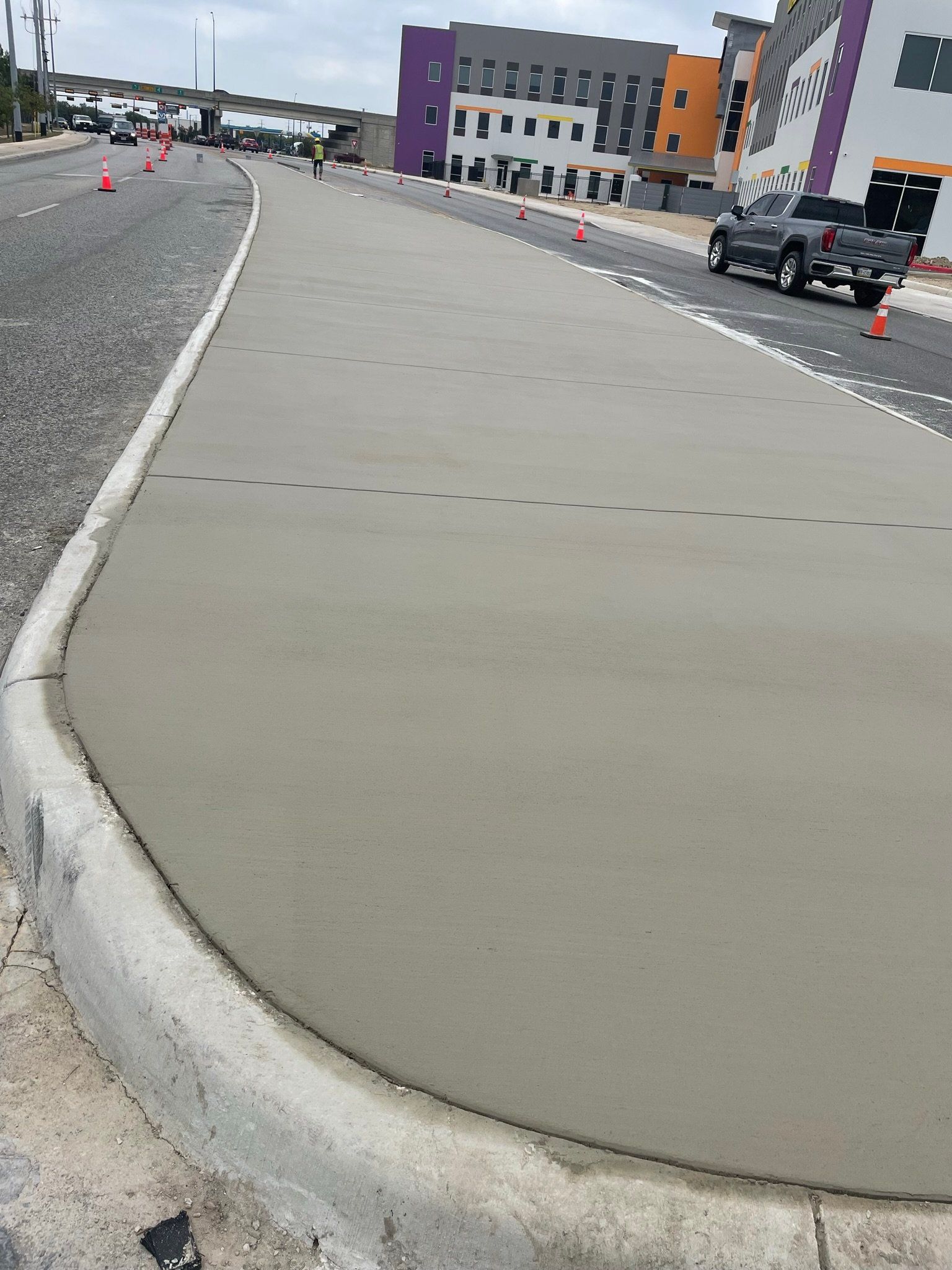 A truck is driving down a street next to a concrete curb.