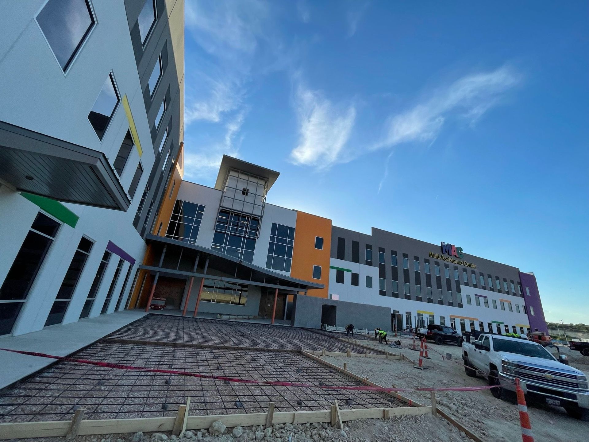 A large building under construction with trucks parked in front of it.