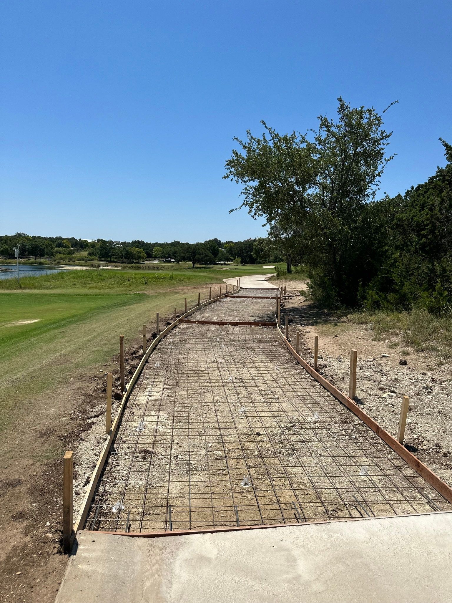 A concrete walkway is being built next to a golf course.