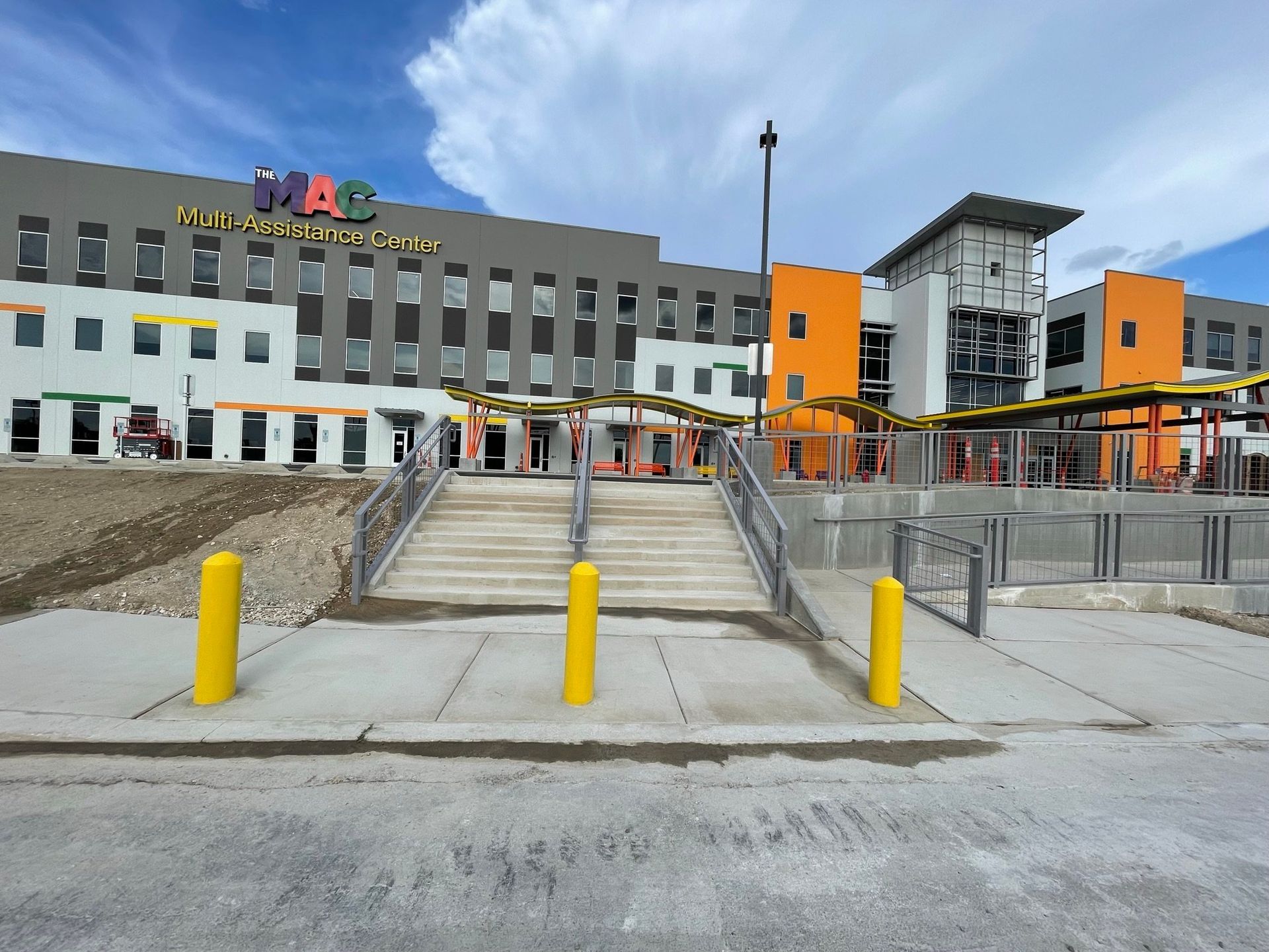 A large building with stairs and yellow poles in front of it
