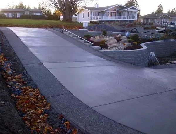 A concrete driveway with a house in the background