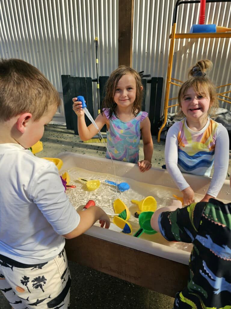 children playing on the water tub with sand