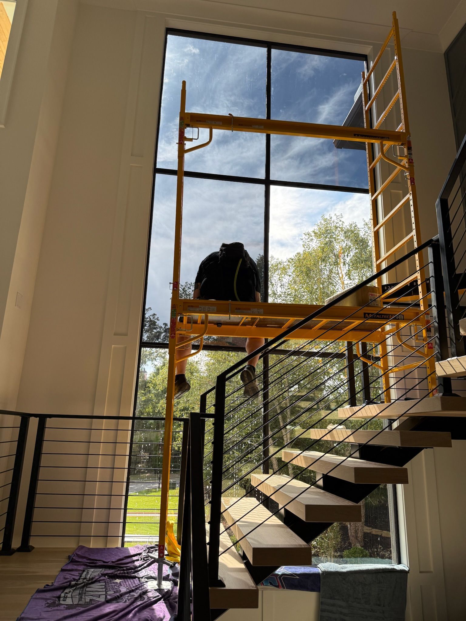 Scaffolding set up near a large window, visible from a staircase.