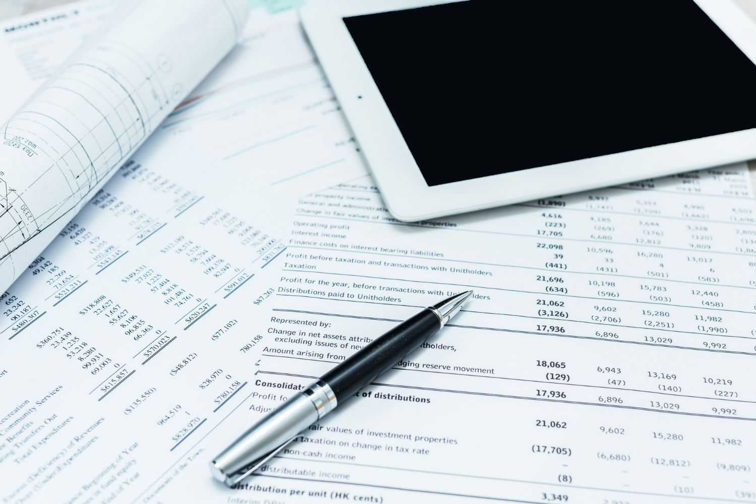Tablet and paperwork with a pen, likely used for financial analysis.