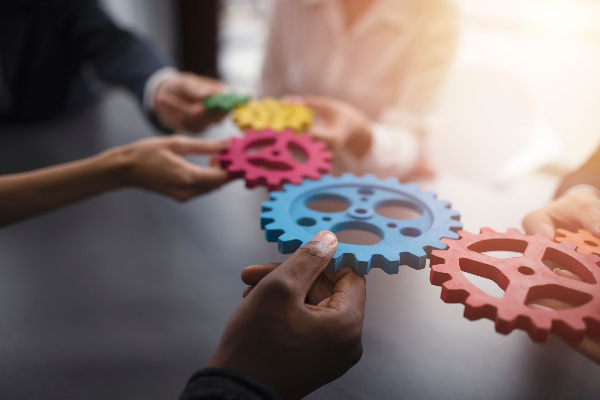 Hands holding colorful gears, symbolizing teamwork and collaboration.