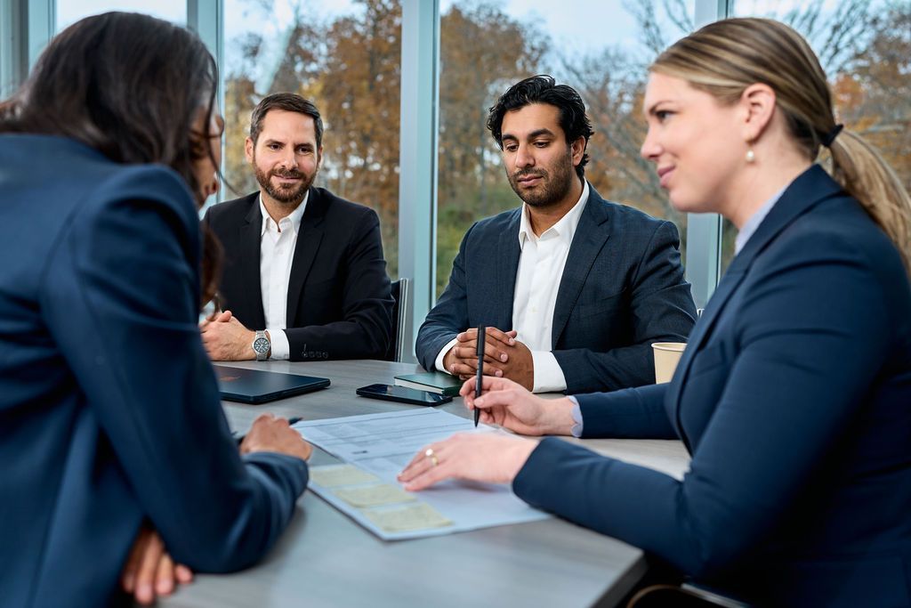 A group of business people are sitting around a table having a meeting.