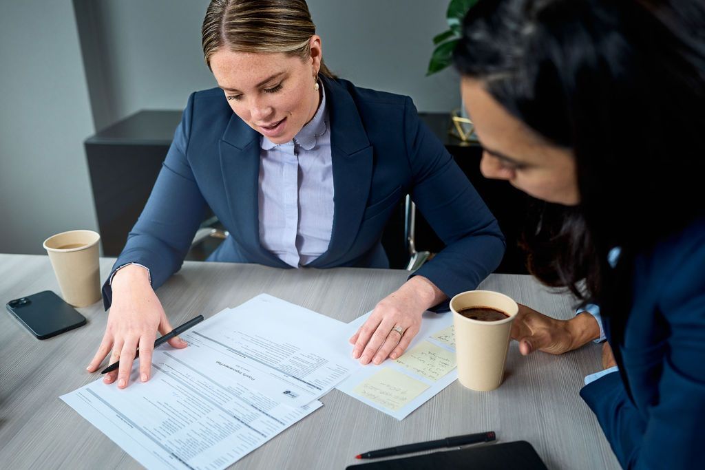 Two women are sitting at a table looking at papers.