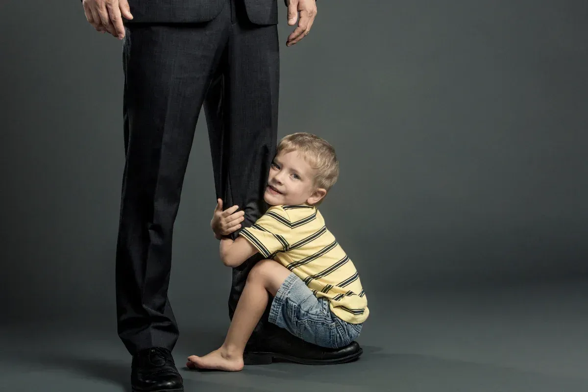 A little boy is kneeling down next to a man in a suit.