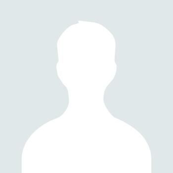 Smiling man with red beard in a teal checkered shirt against a gray background