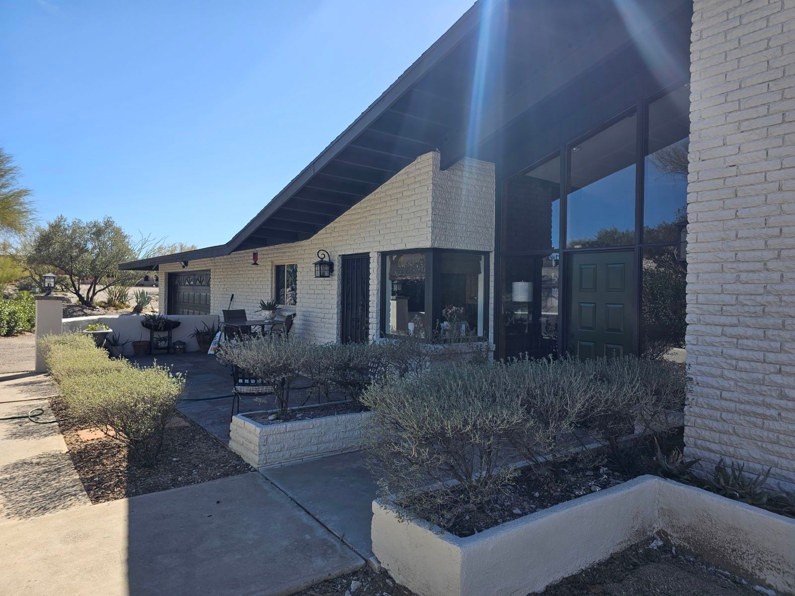 A white brick house with a black roof and a lot of windows
