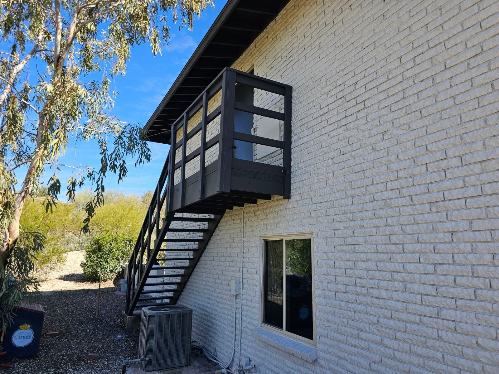 A white brick building with a black staircase on the side of it.