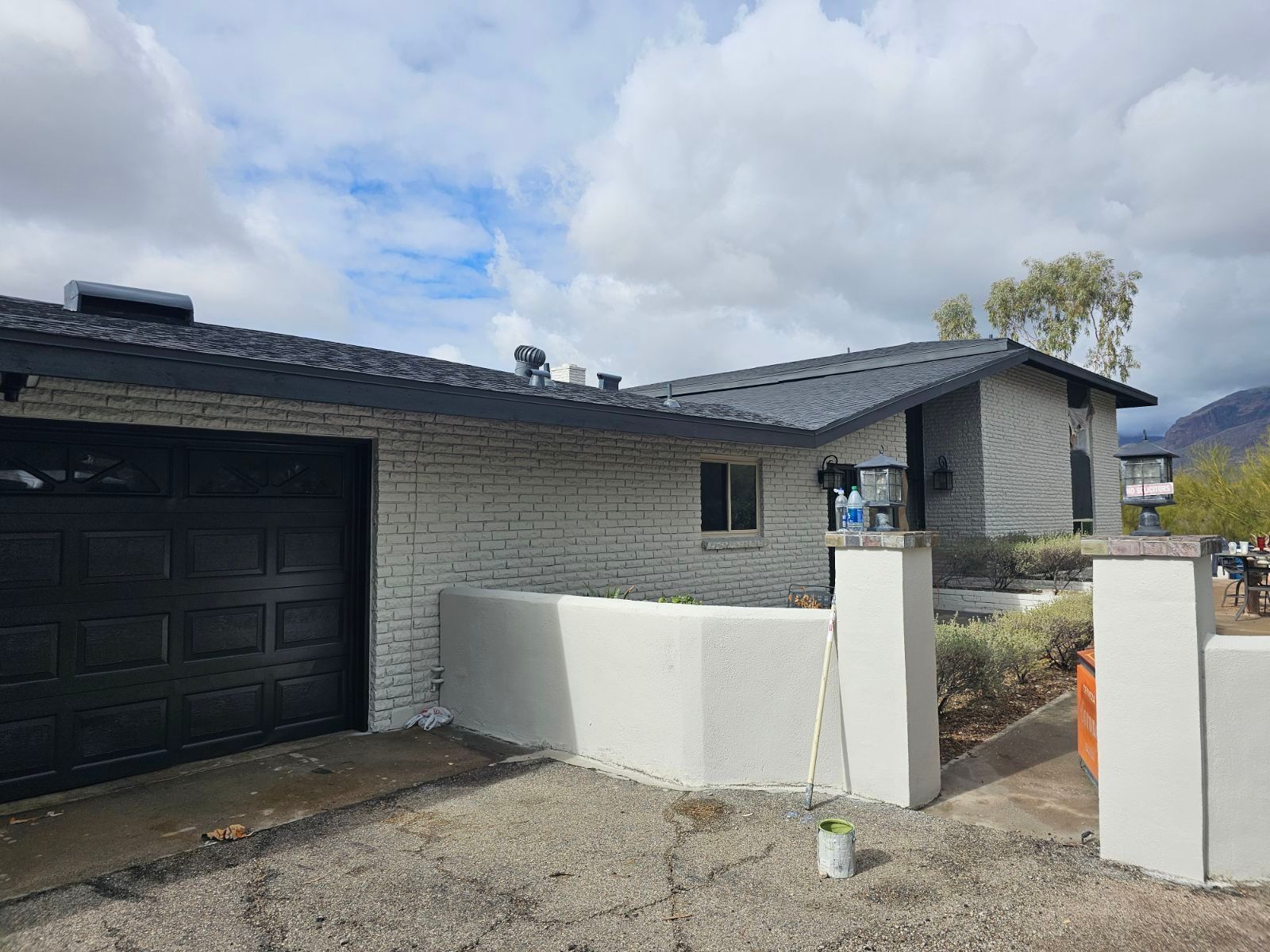 A white brick house with a black garage door is being painted.