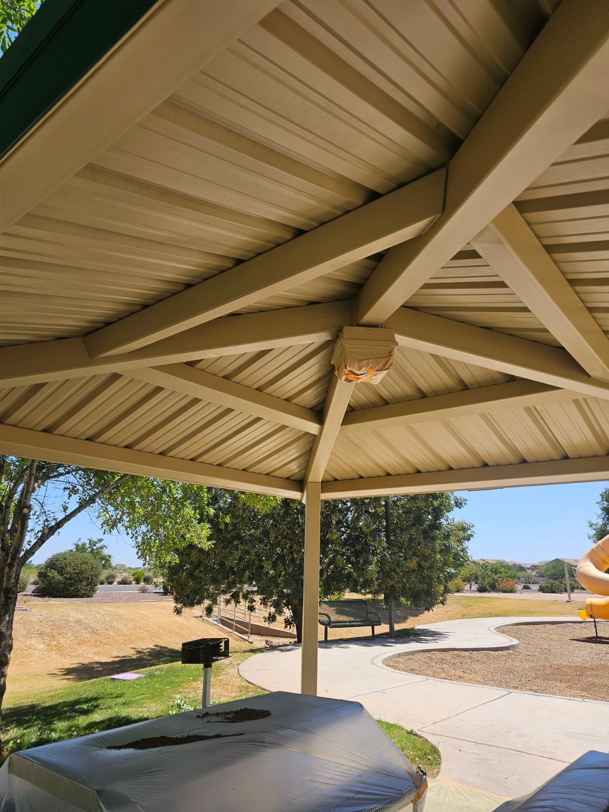 A gazebo in a park with a slide in the background