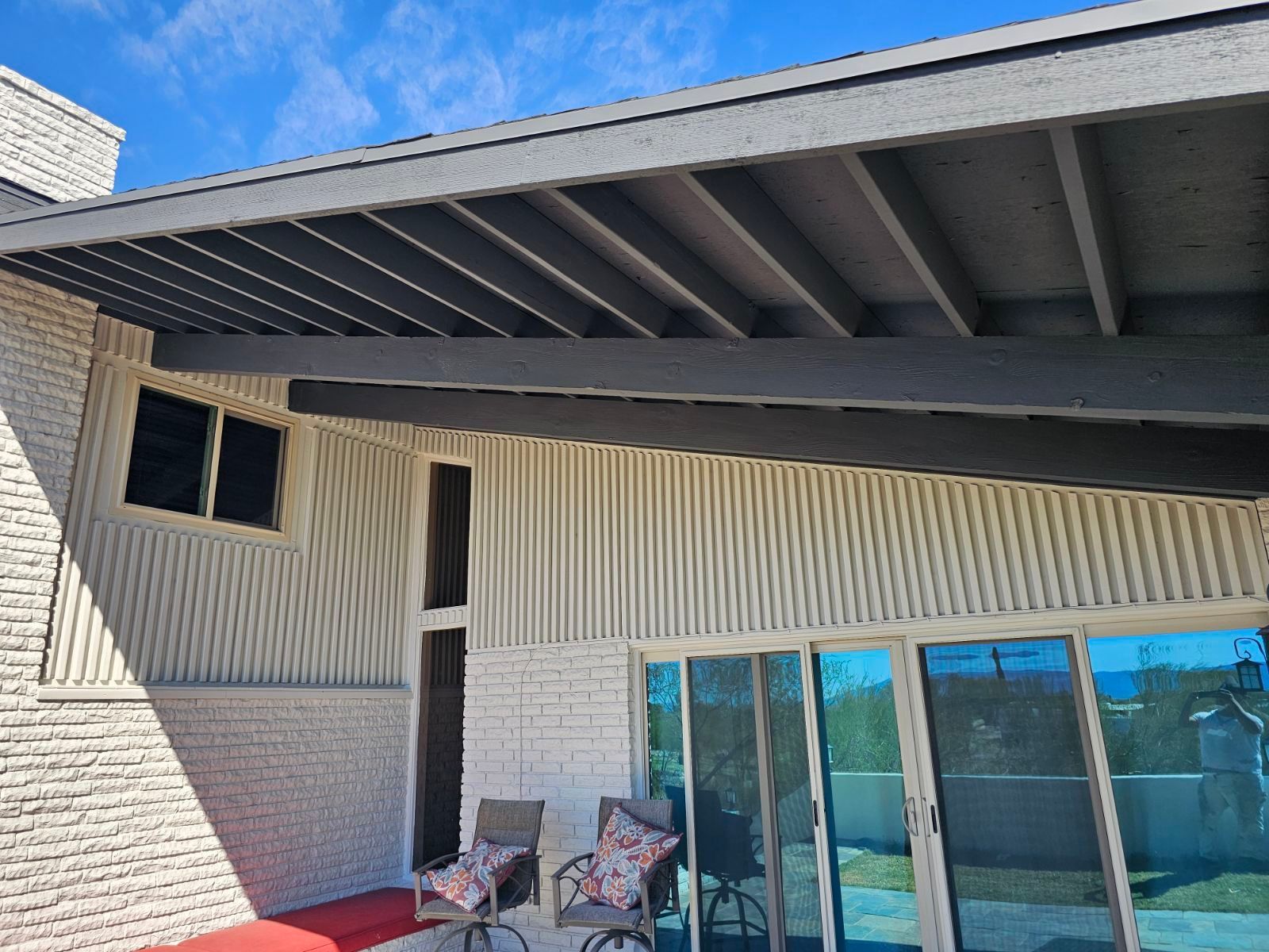 A white brick house with sliding glass doors and a covered patio area.