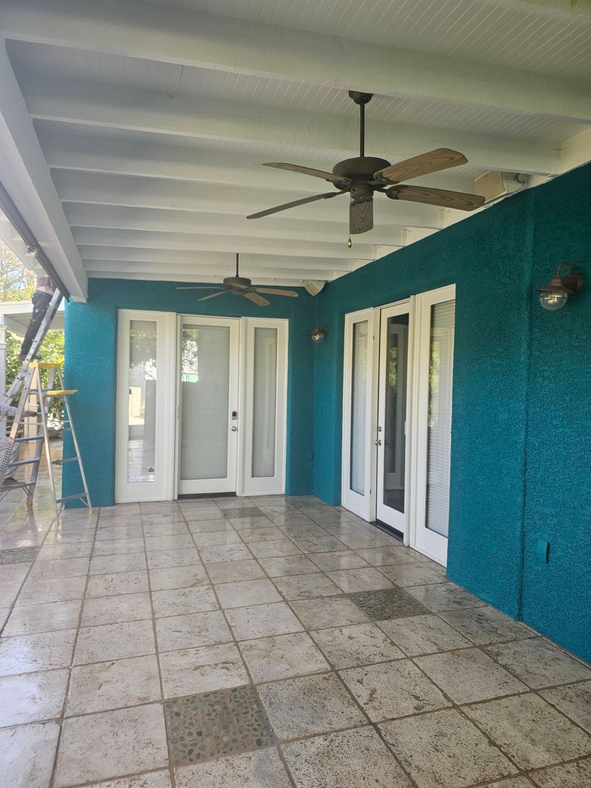 There is a ceiling fan on the porch of a house.