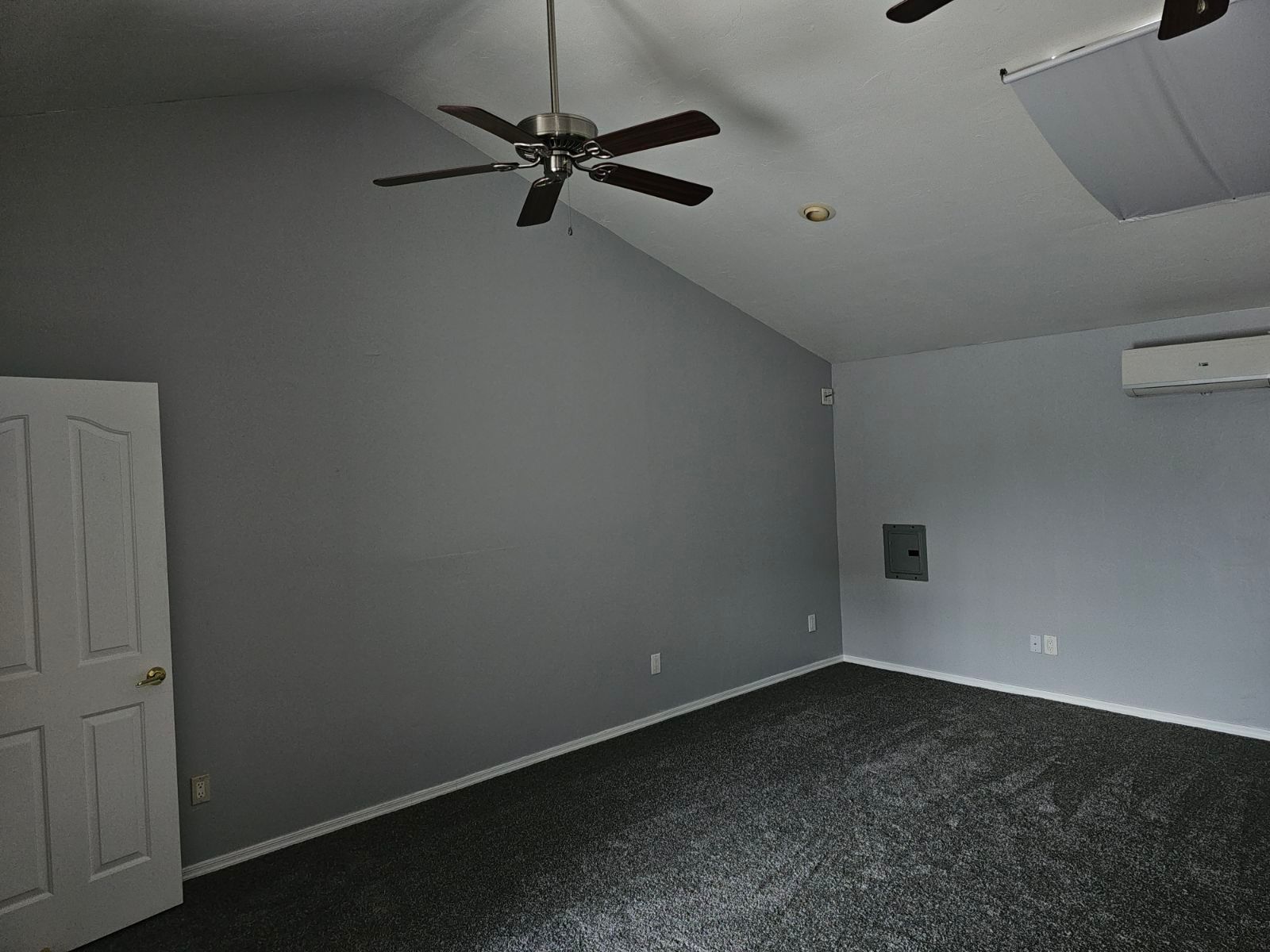 An empty room with a ceiling fan and a door.