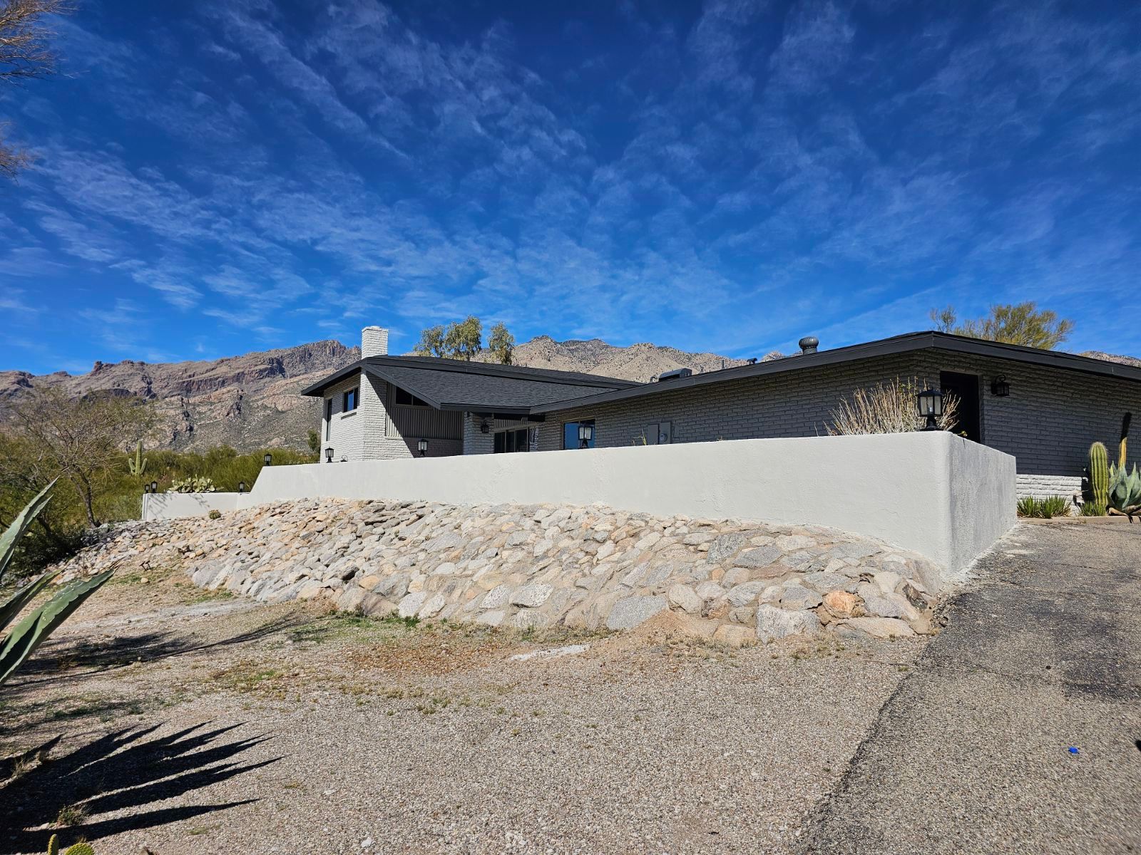 A house is sitting on top of a hill with mountains in the background.