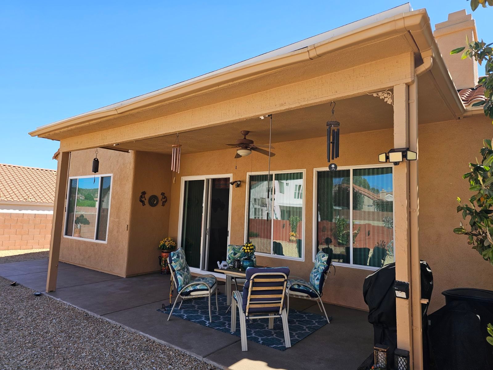 A patio area with a table and chairs under a covered patio.