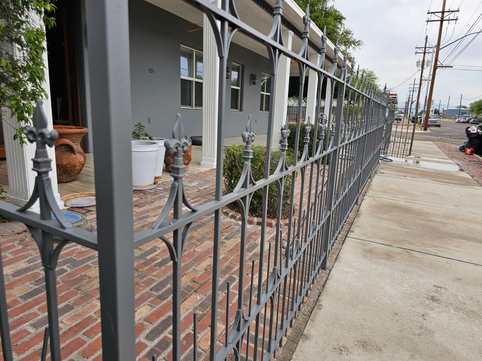 A wrought iron fence is along the sidewalk in front of a house.