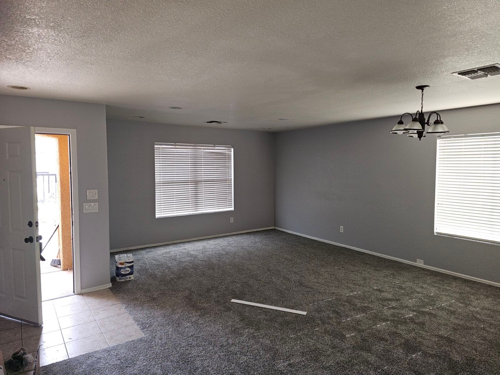 An empty living room with gray walls and a chandelier.