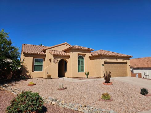 A large house with a garage and a cactus in front of it.