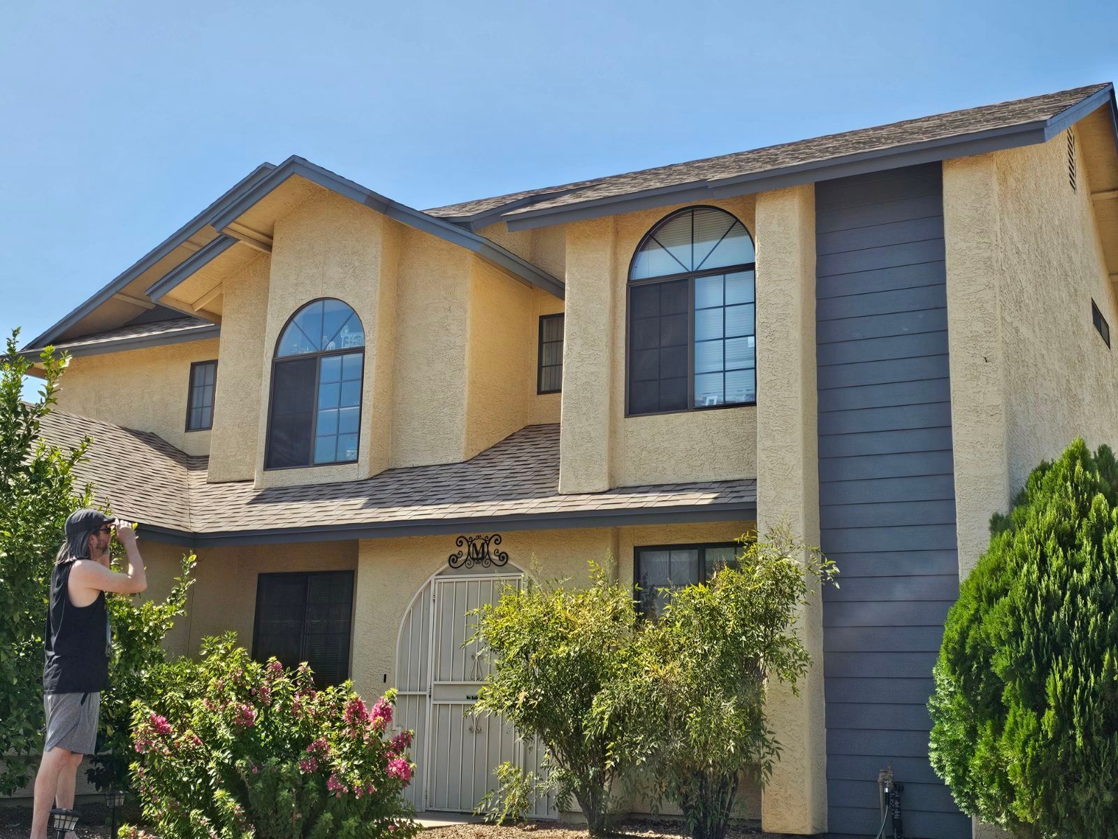 A man is standing in front of a large house.
