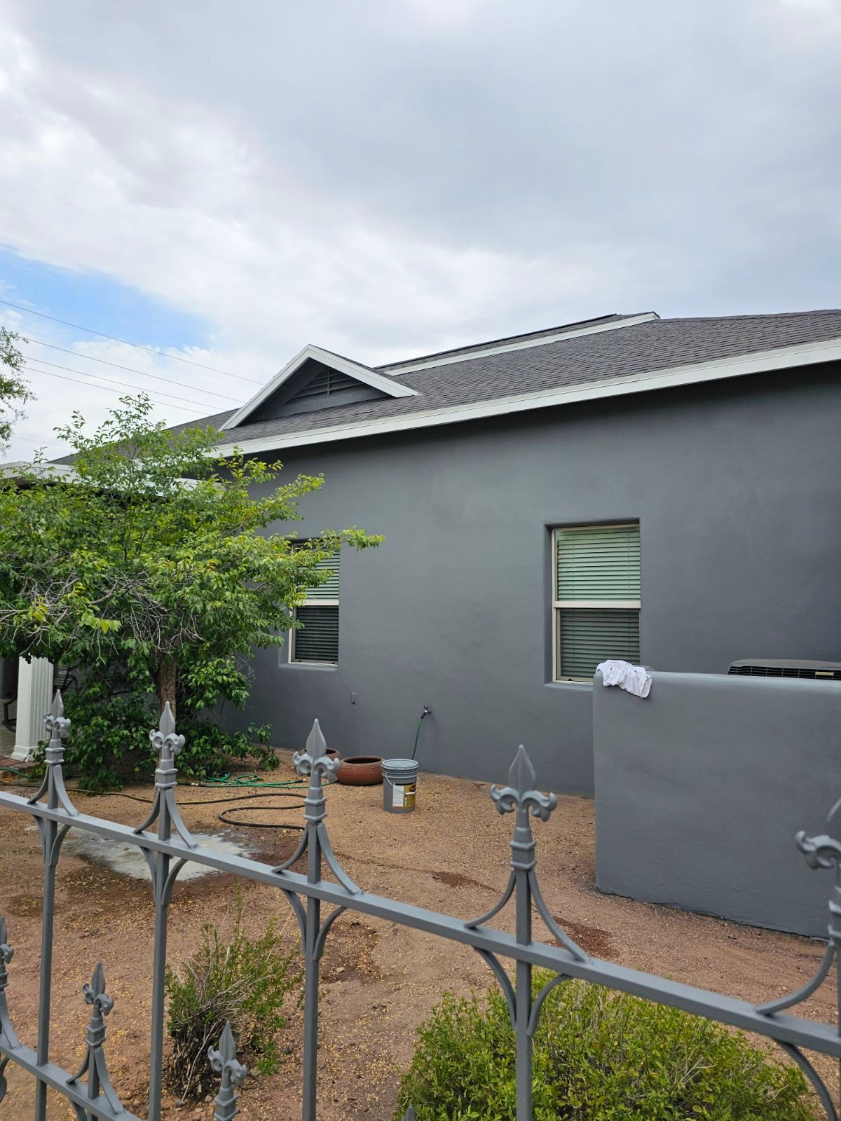 A gray house with a wrought iron fence in front of it.