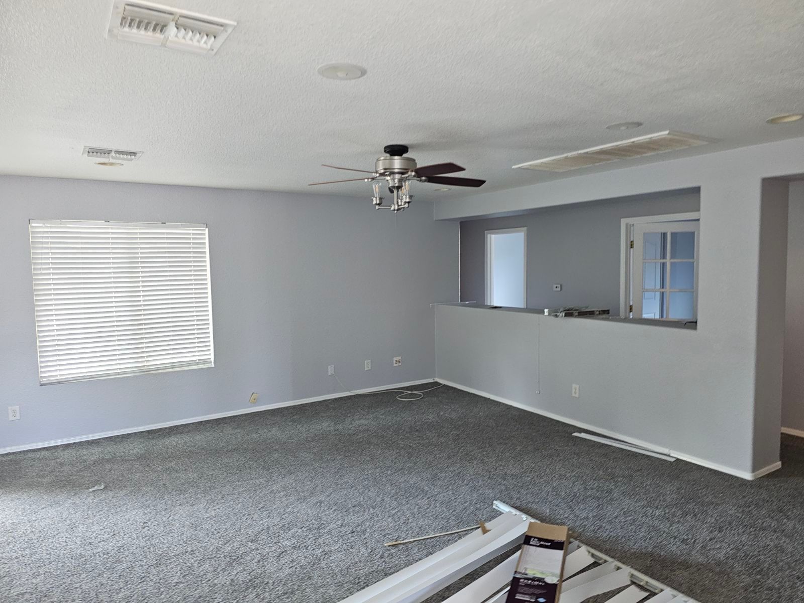 An empty living room with a ceiling fan and a window.