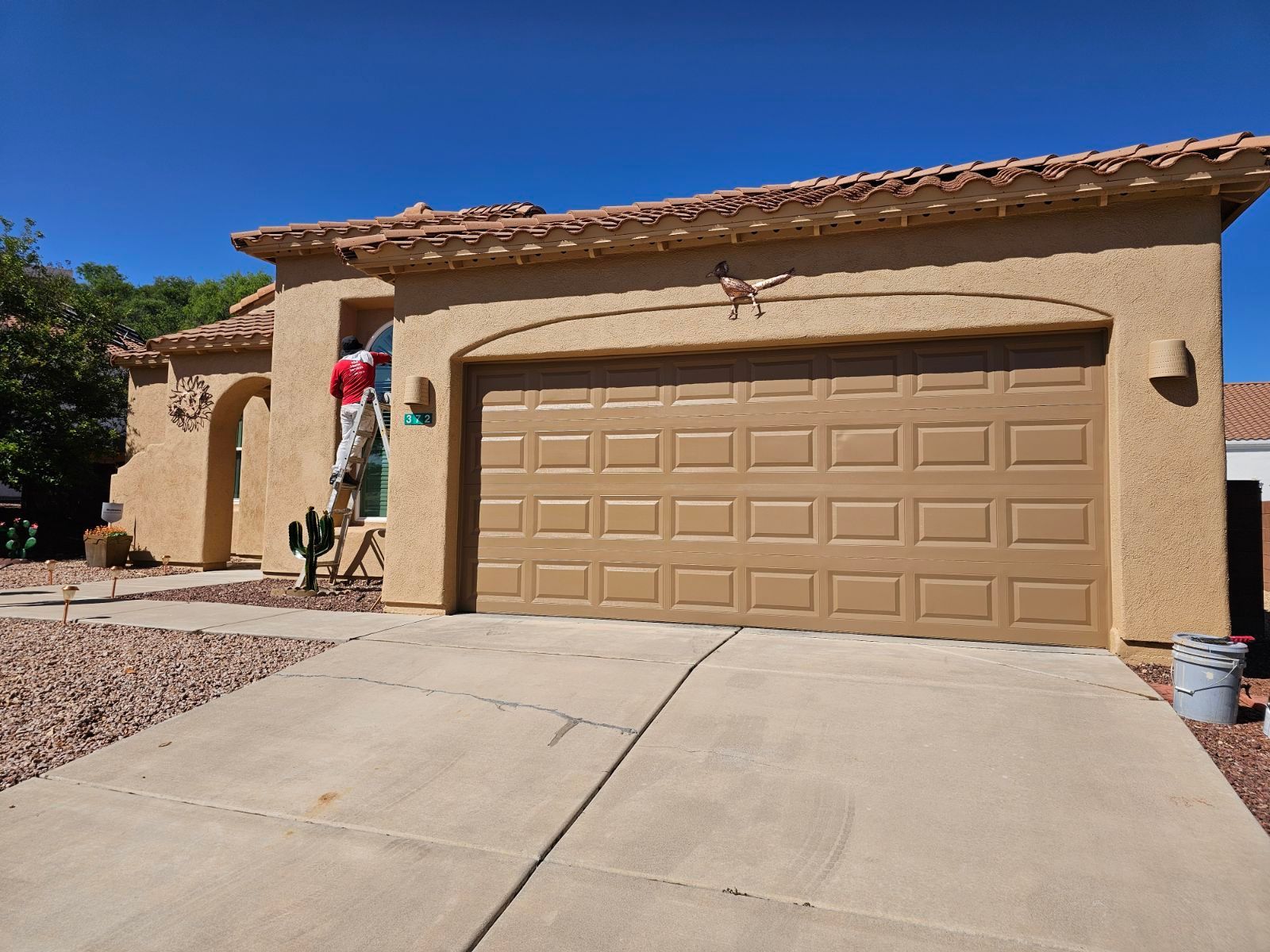 A man is painting the outside of a house with a ladder.