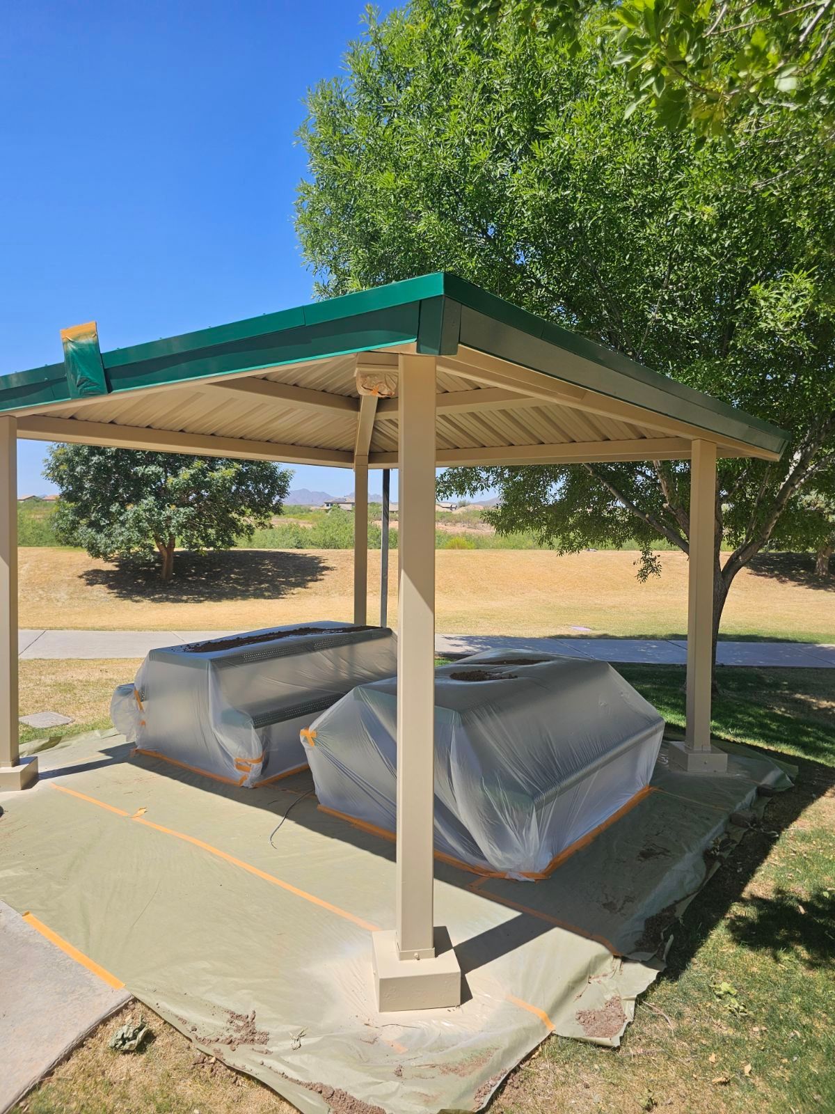 A picnic table under a covered shelter in a park.