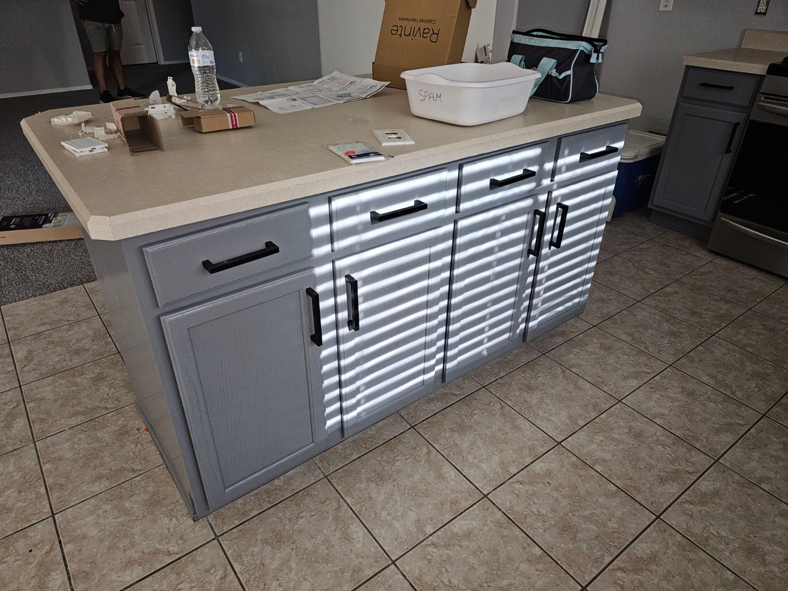 A kitchen island with blinds on the doors and drawers.