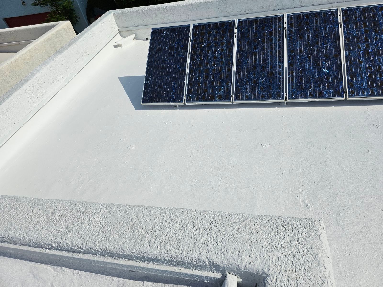 A row of solar panels on top of a white roof