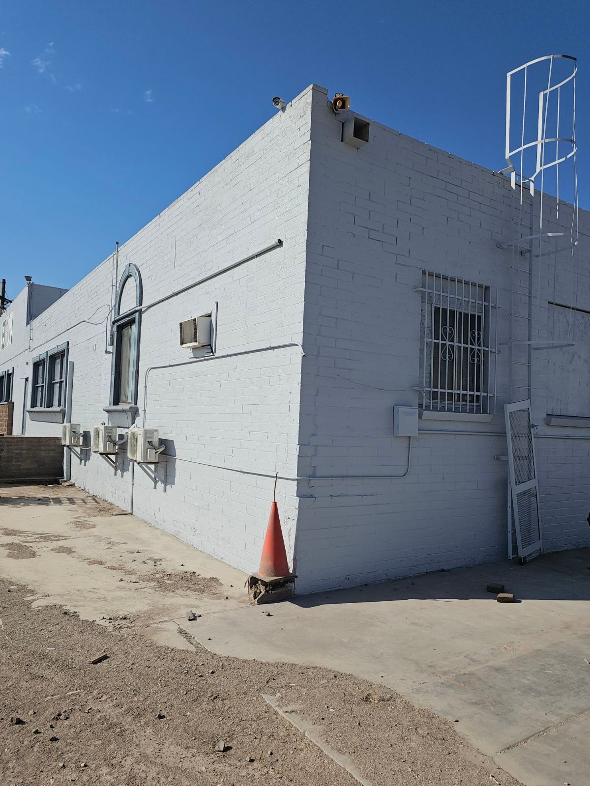 A white brick building with a ladder on the side of it
