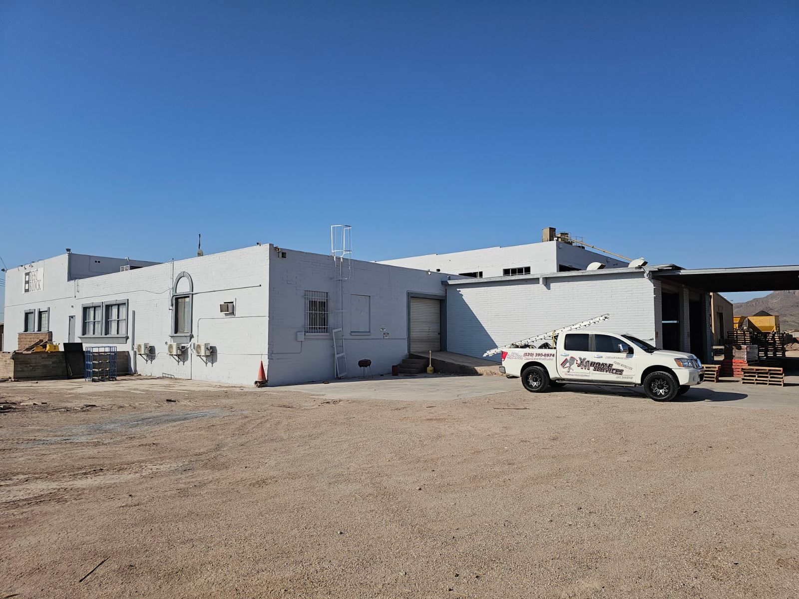 A white truck is parked in front of a white building.
