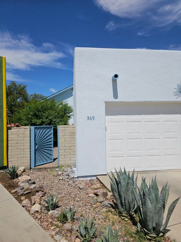 A white house with a white garage door and a blue gate.