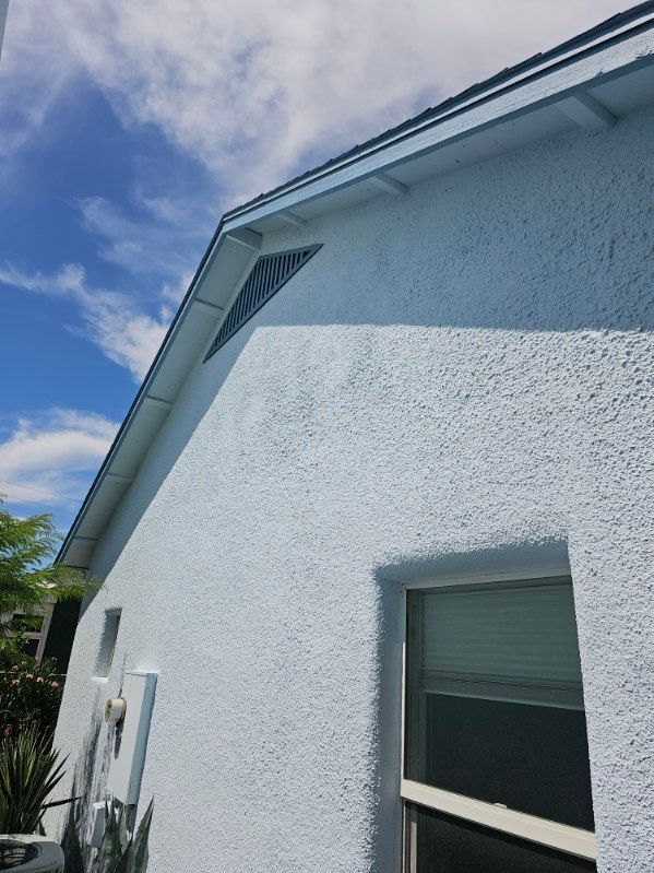 A white house with a window and a roof on a sunny day.