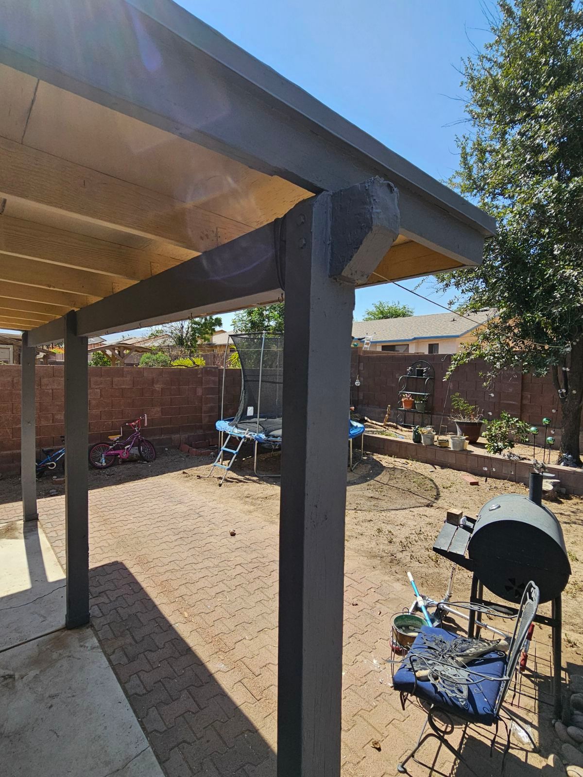 A patio with a pergola and a grill in the backyard.