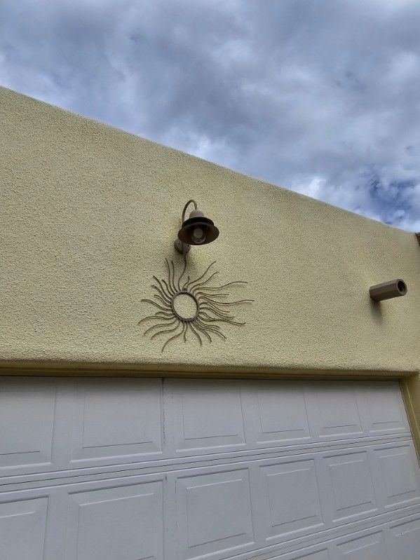 A light is hanging from the side of a building next to a garage door.