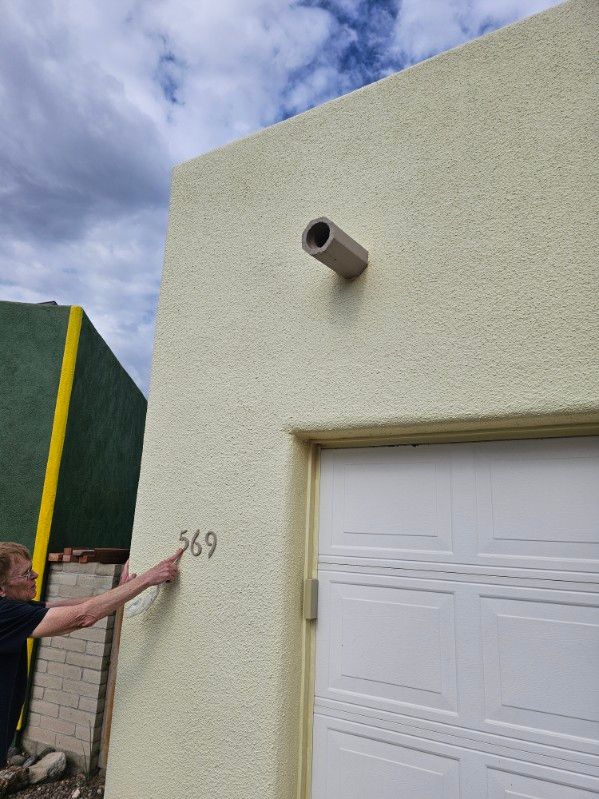 A person is pointing at the number 369 on the side of a building.