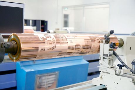 A large copper roller is being rolled on a lathe in a factory.