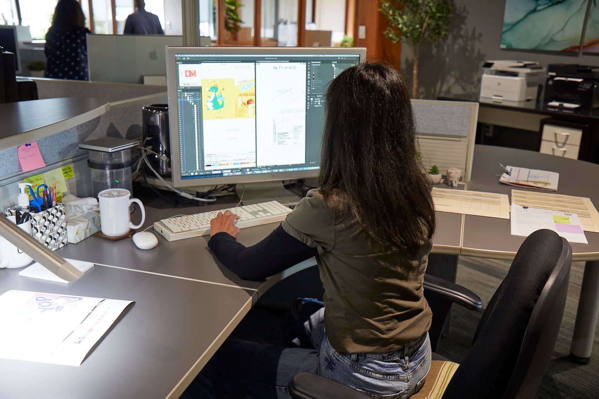 A woman is sitting at a desk working on a computer.