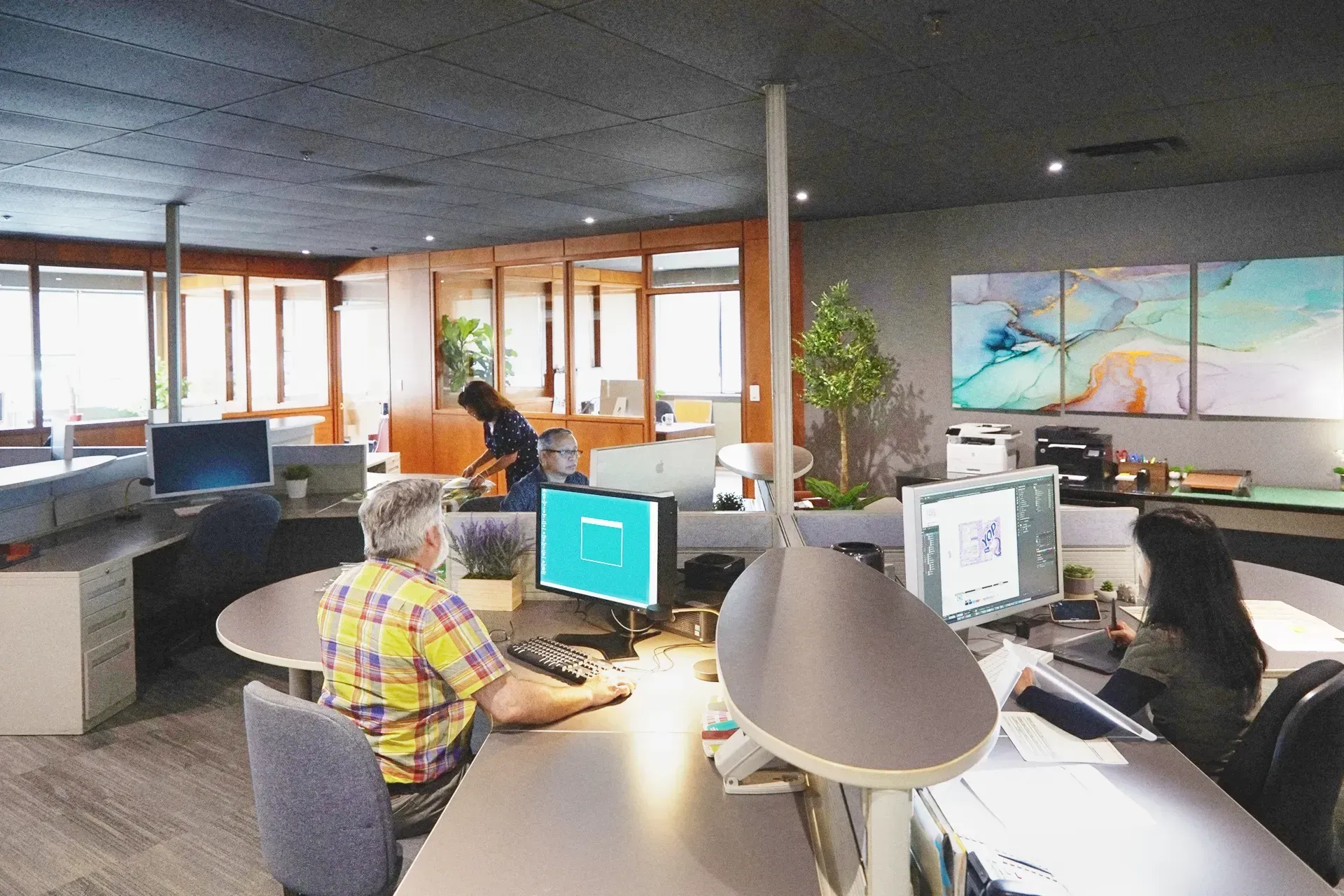 A man is sitting at a desk in an office working on a computer.