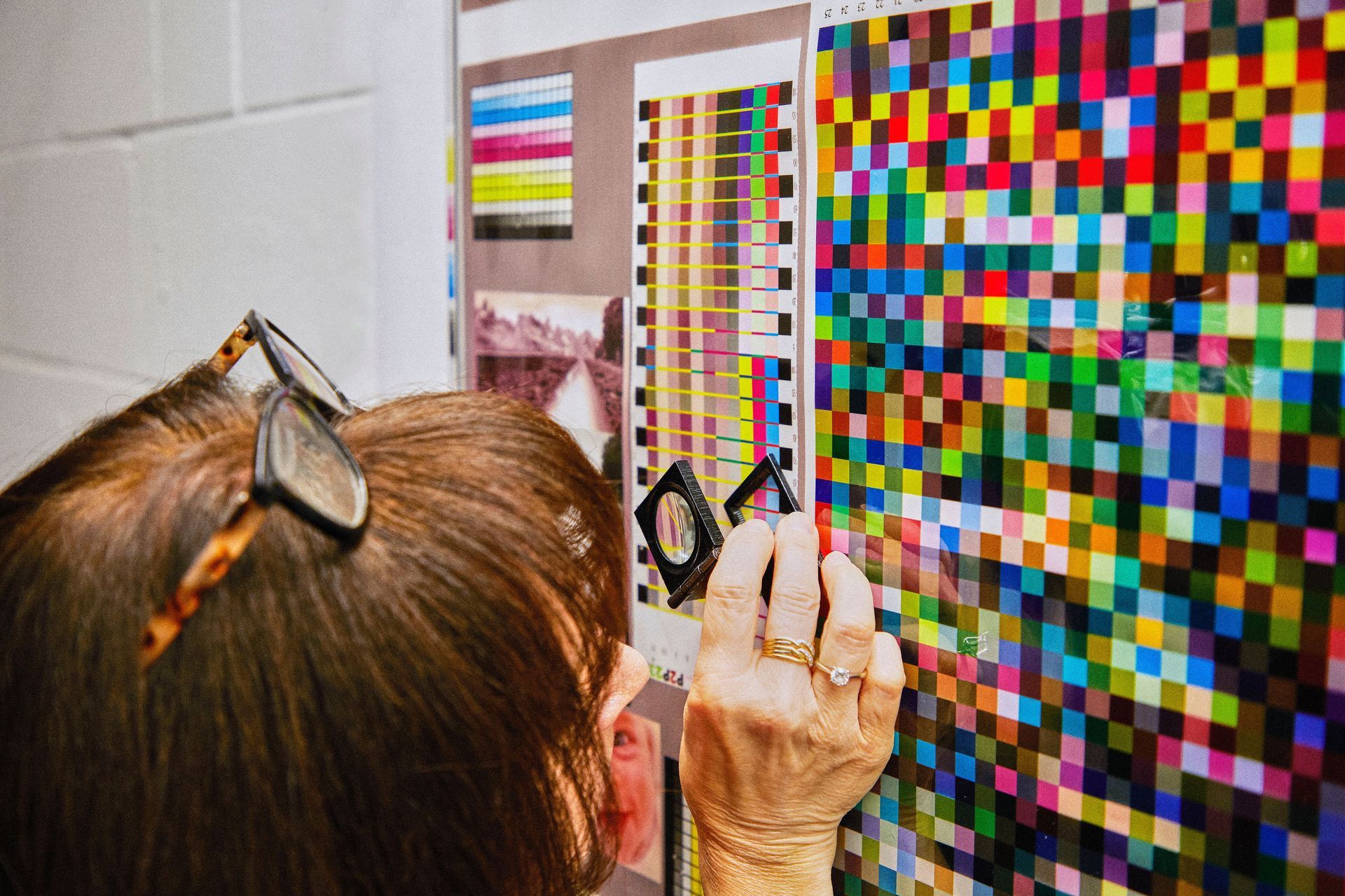A woman is looking at a colorful pixelated image on a wall.
