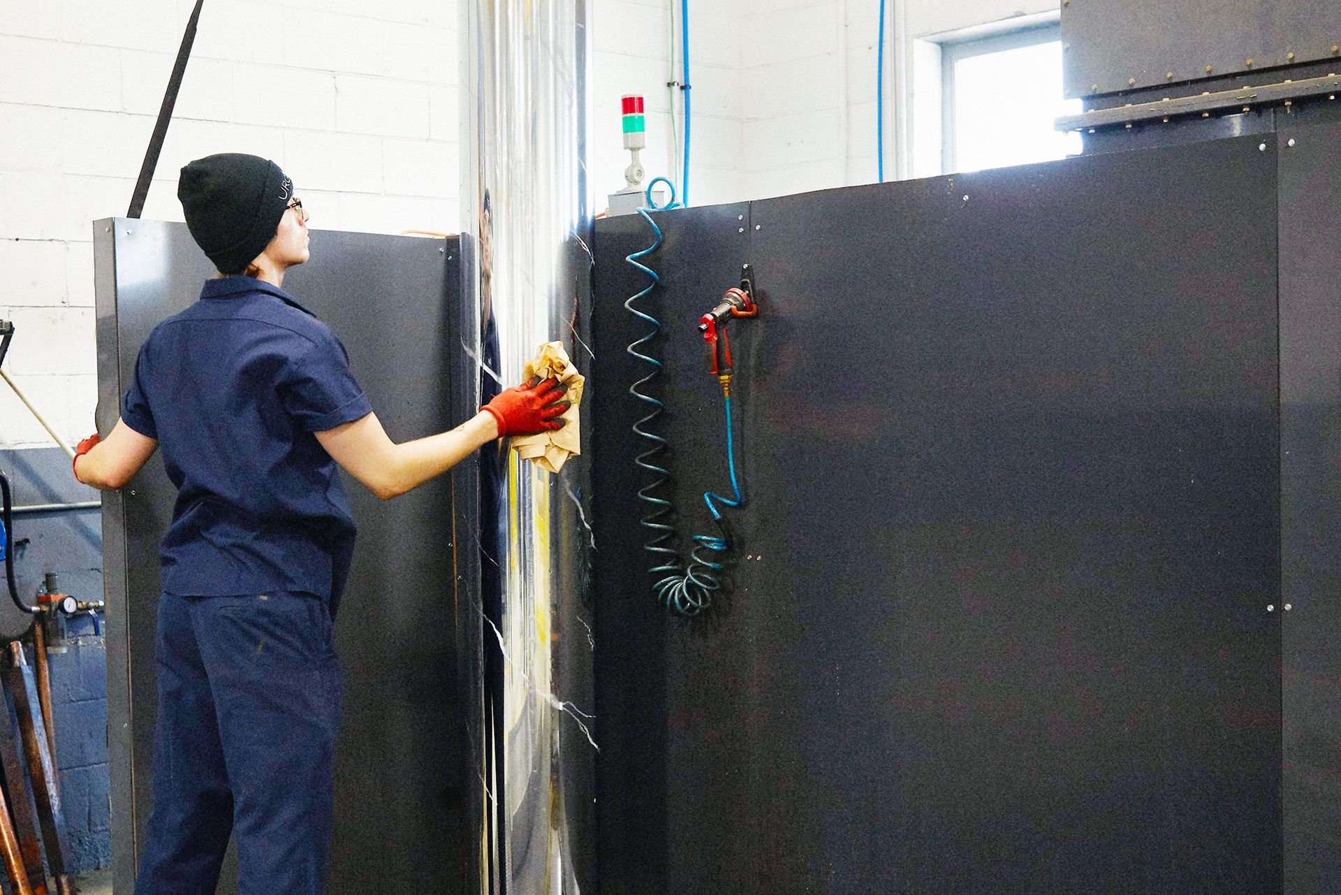 A woman is cleaning a machine with a cloth in a factory.