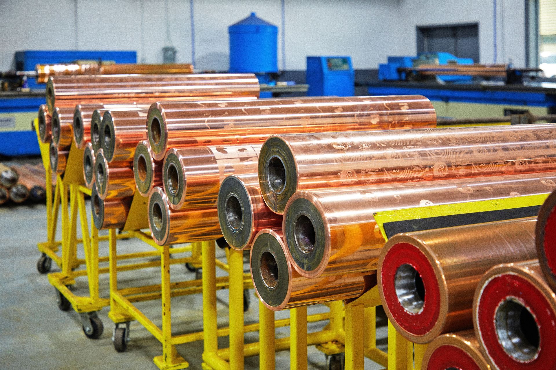 A bunch of copper pipes are sitting on a yellow cart in a factory.