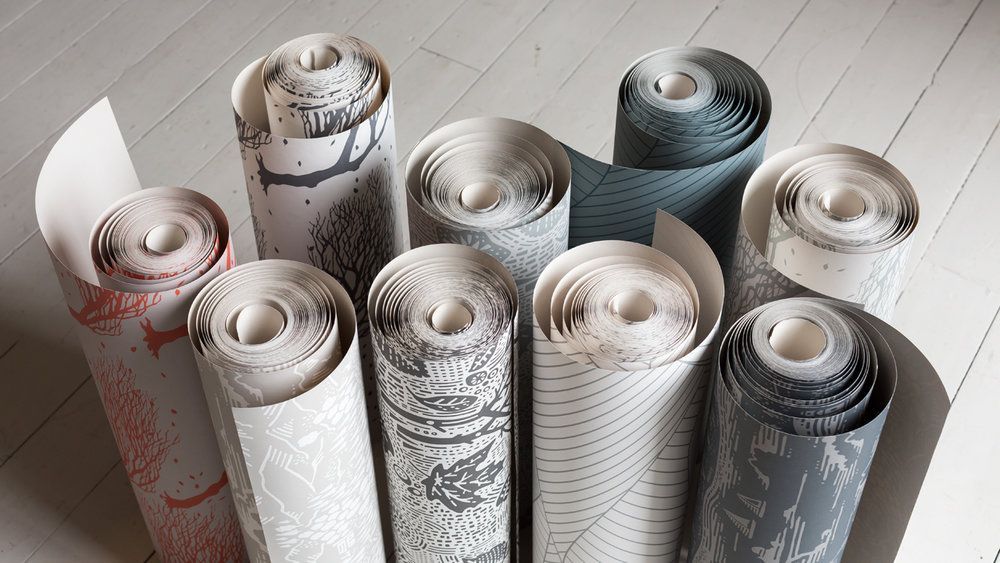 Rolls of wallpaper are stacked on top of each other on a wooden floor.