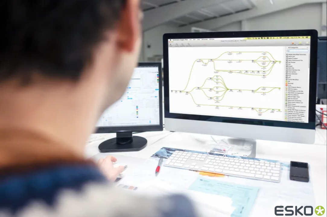 A woman is sitting at a desk looking at a computer screen.