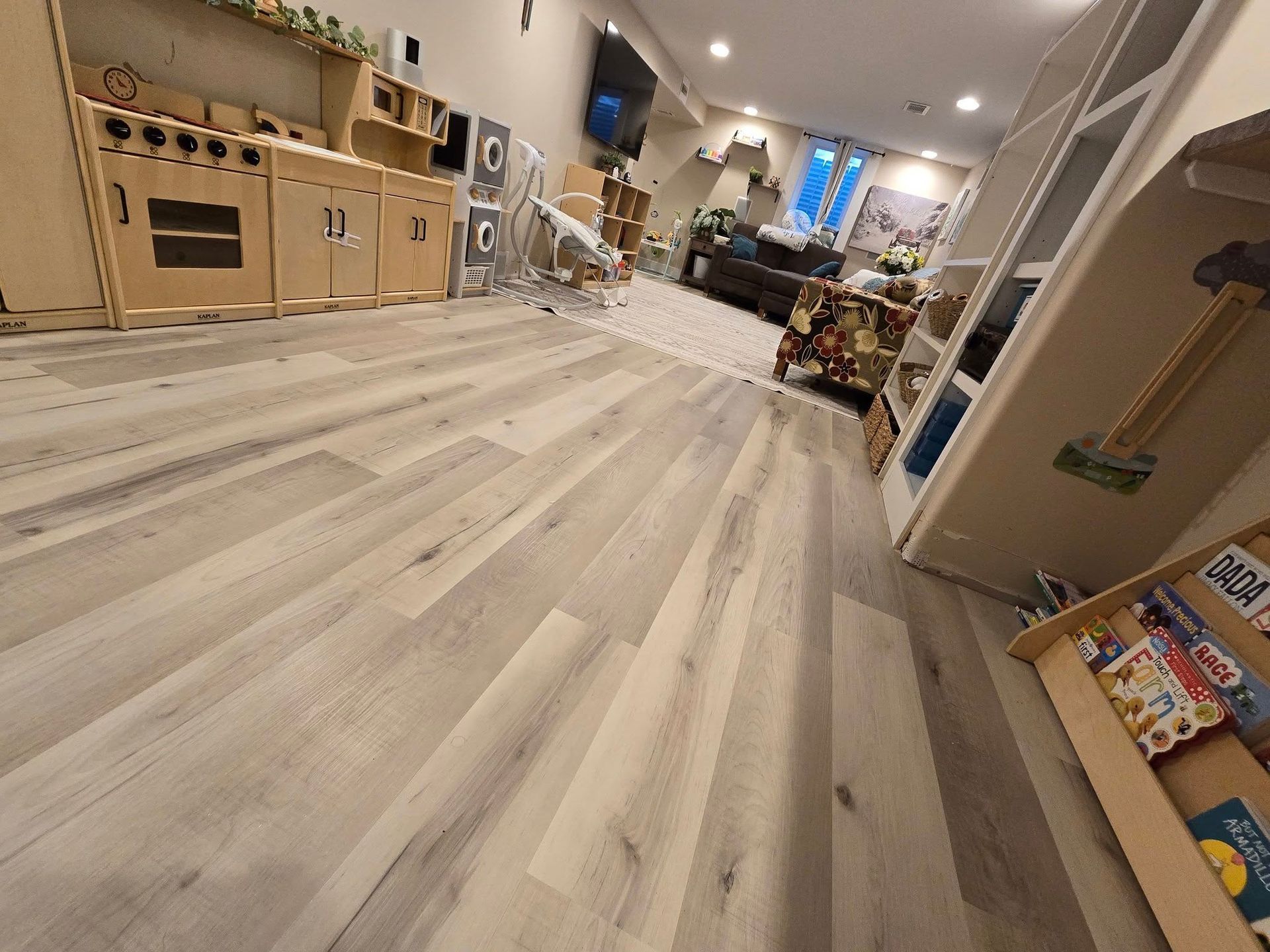A living room with hardwood floors and a wooden play kitchen.