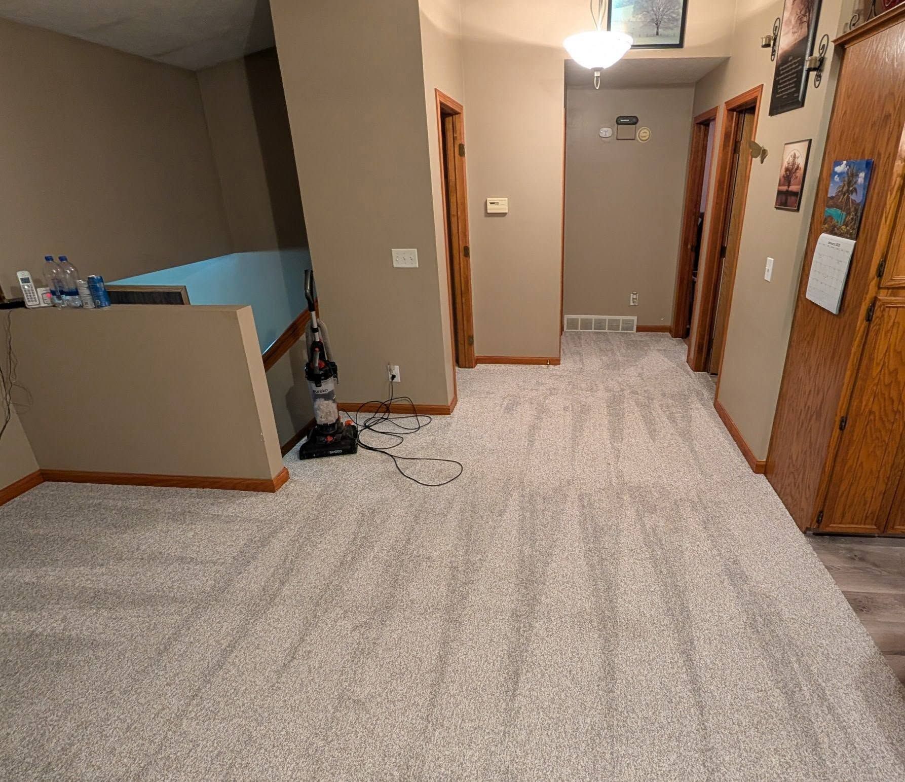 A hallway with a vacuum cleaner on the floor in a house.