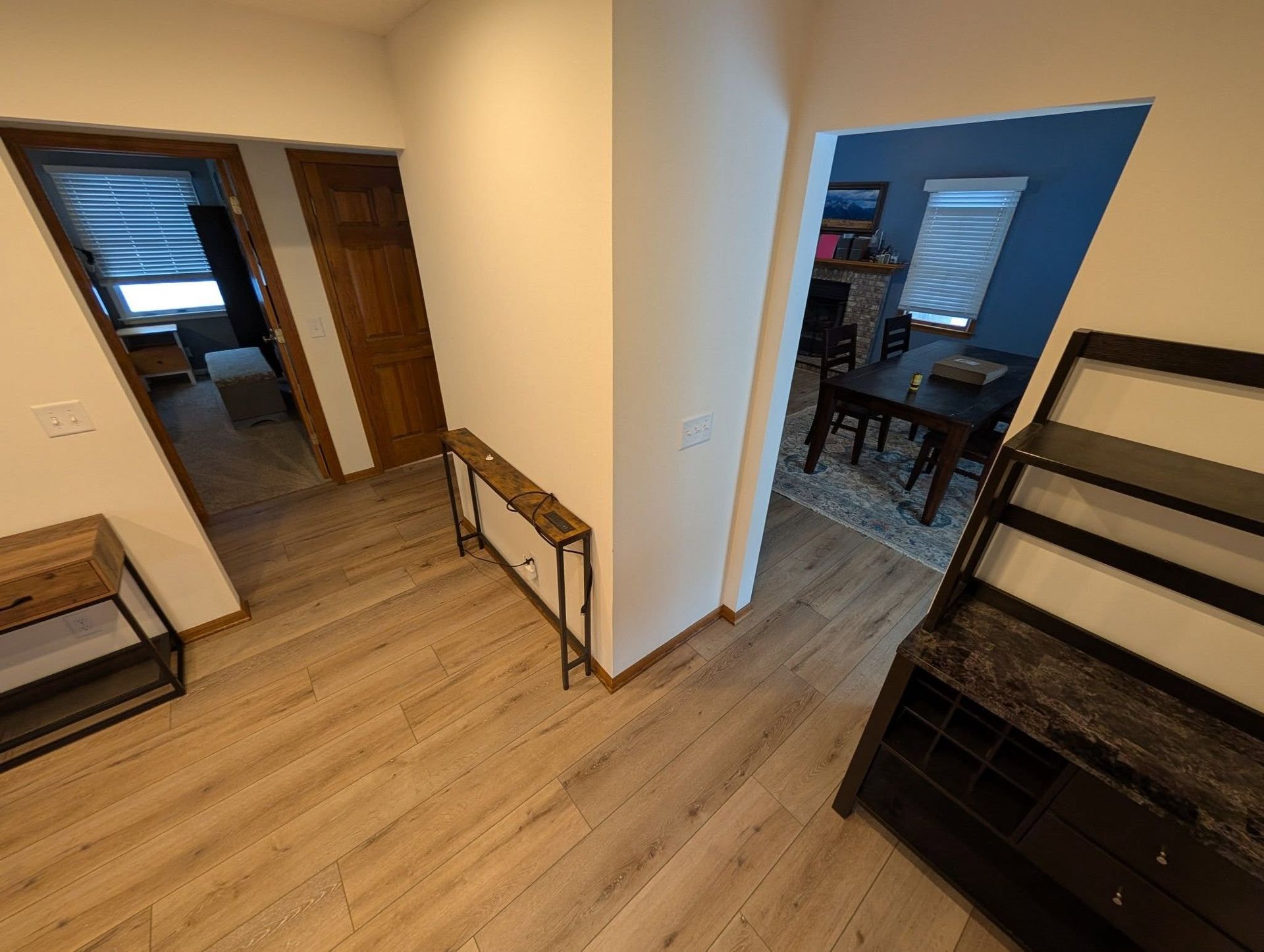 A hallway with hardwood floors leading to a living room and dining room.
